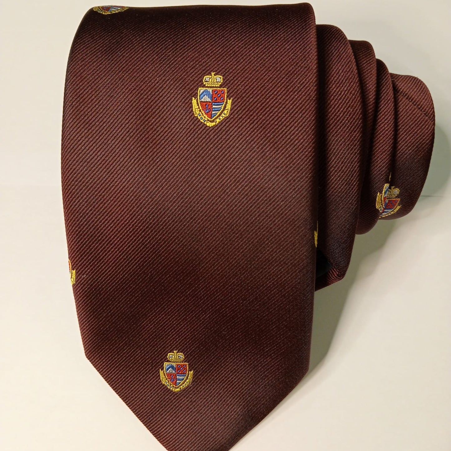 Corbata lisa burdeos con escudos.