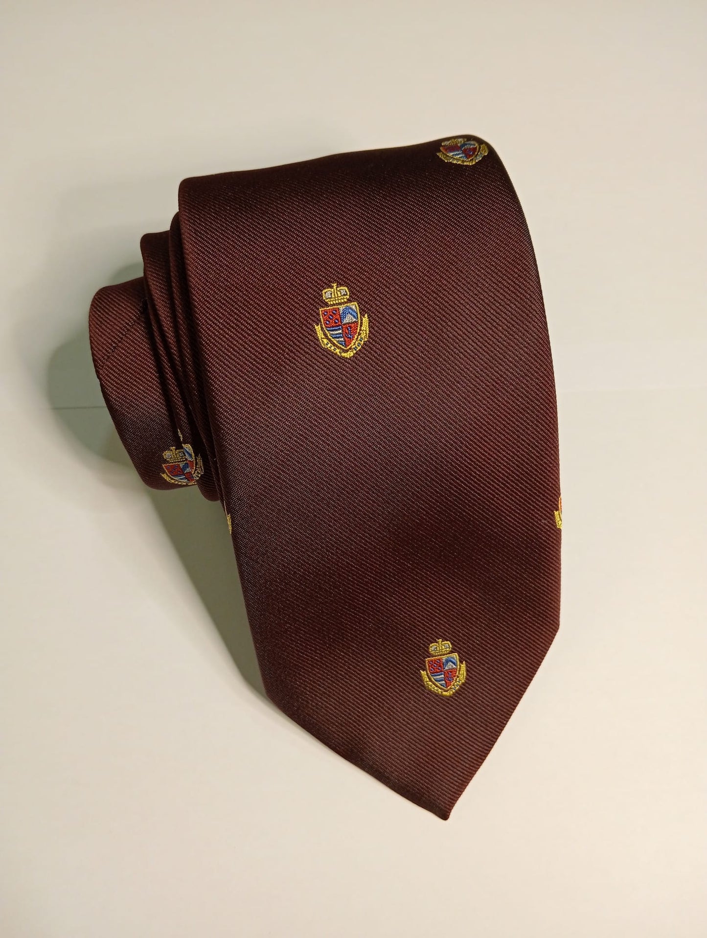 Corbata lisa burdeos con escudos.