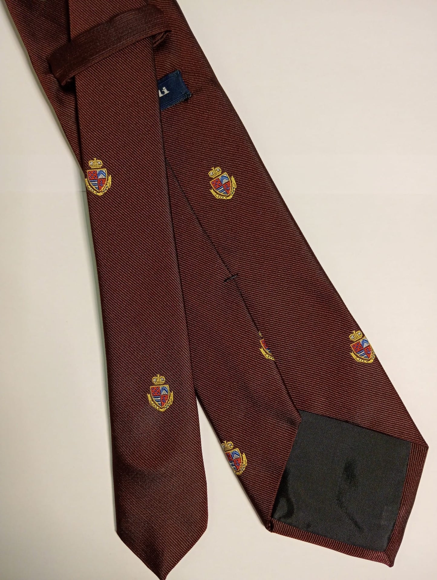 Corbata lisa burdeos con escudos.
