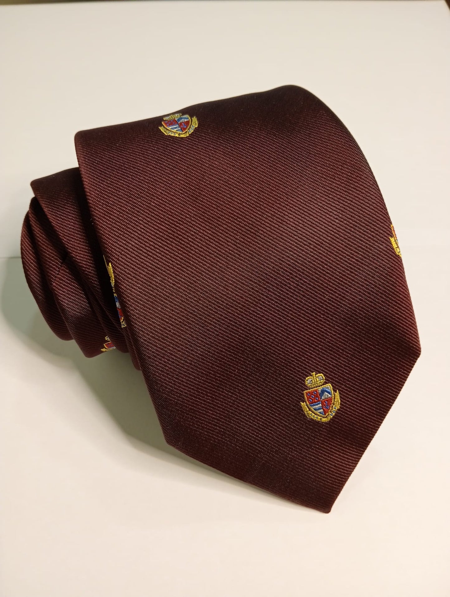 Corbata lisa burdeos con escudos.